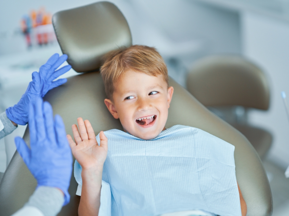 A boy high-fives the dentist after a pediatric appointment